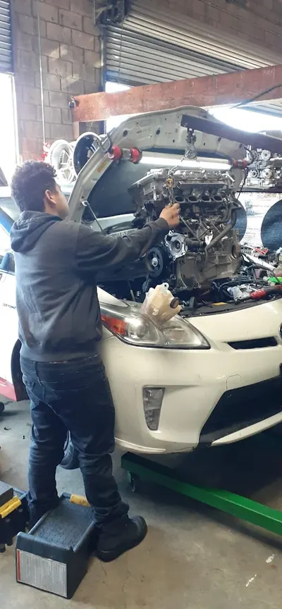 Hybrid 310 technician servicing the engine of a white Toyota Prius in the Hawthorne shop